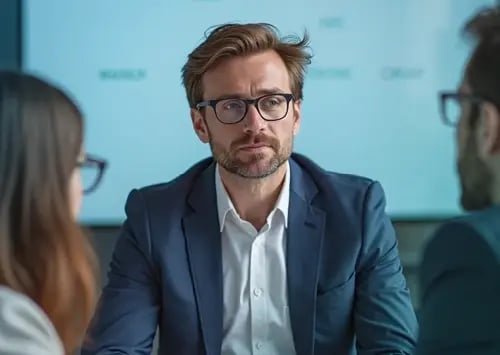 Männlicher Geschäftsführer im Gespräch während eines Meetings mit Kollegen und Kunden.