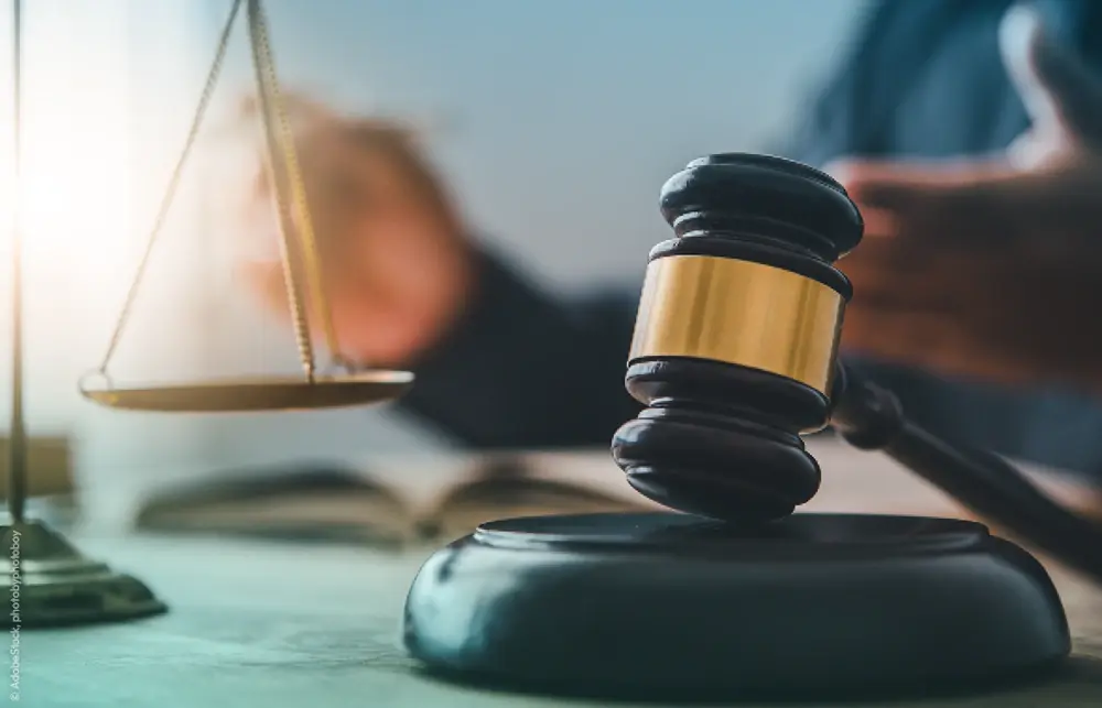 Close-up of a judge's gavel on a desk with the scales of Justice.
